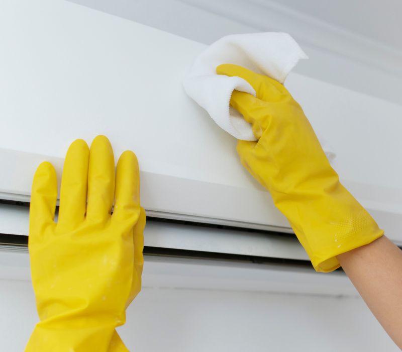 someone cleaning ac with cloth wearing yellow gloves