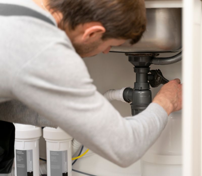 plumber cleaning drain pipe with wrench