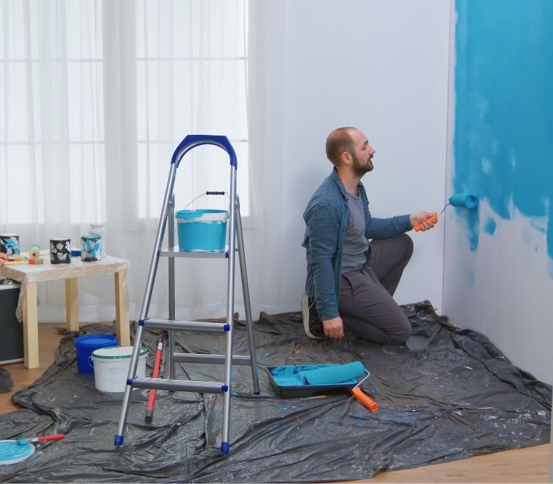 a boy painting house with roller