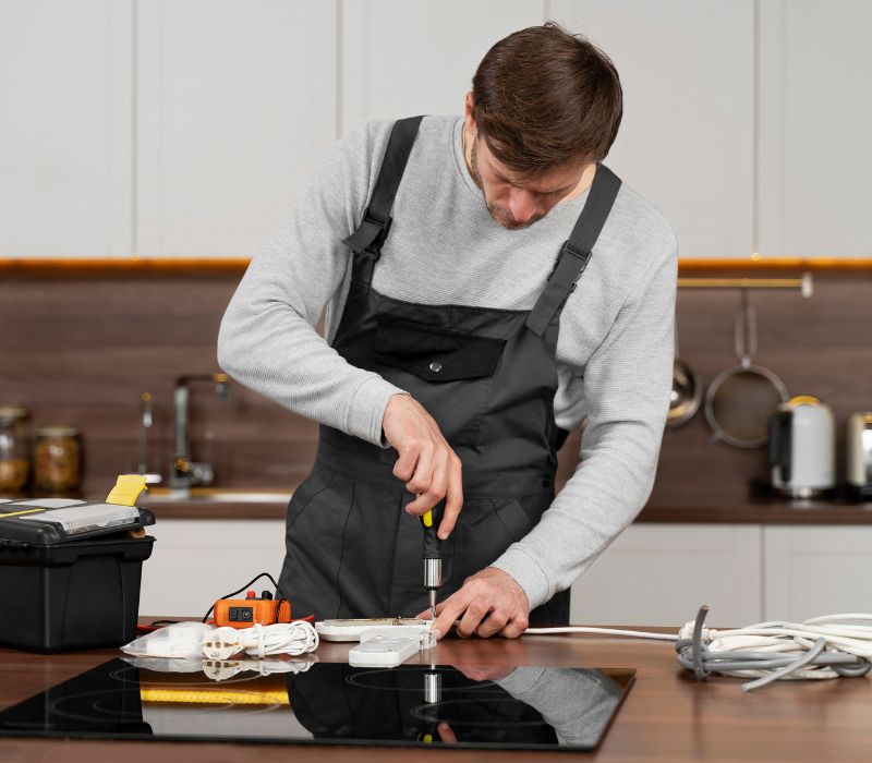 a male repairing some appliance in kitchen