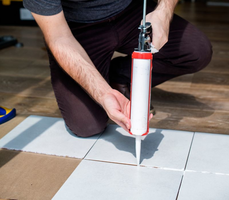 a mason is filling tiles with tile grout